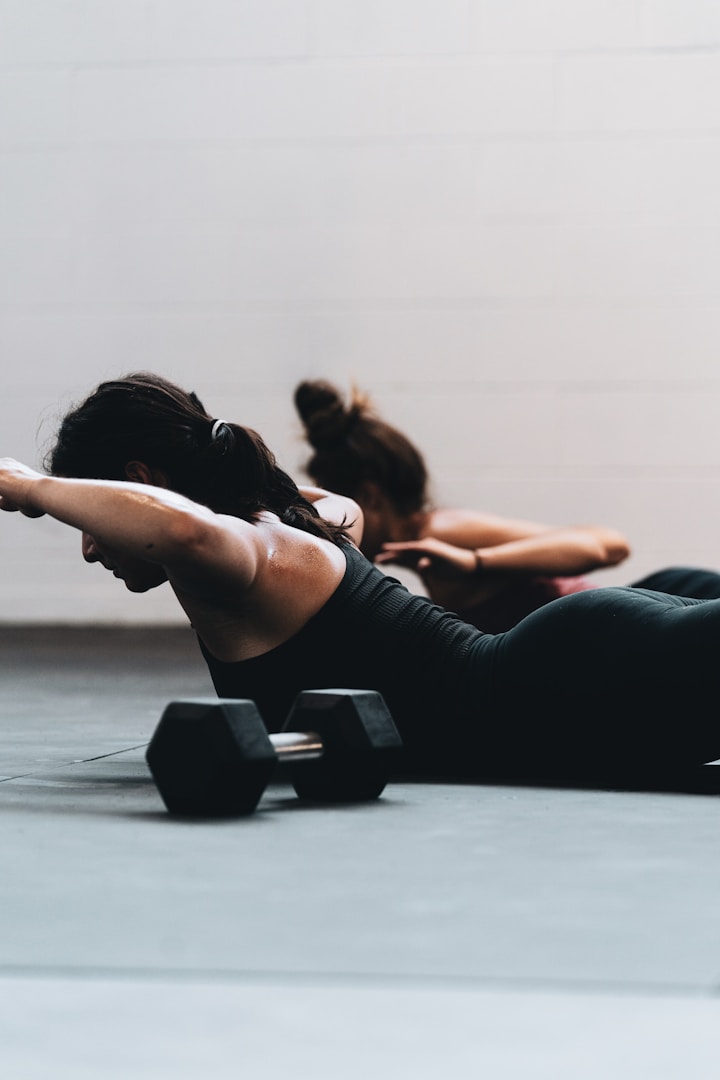 Fitness Zwei Personen führen Liegestütze mit Hanteln auf einer Fitnessmatte aus.